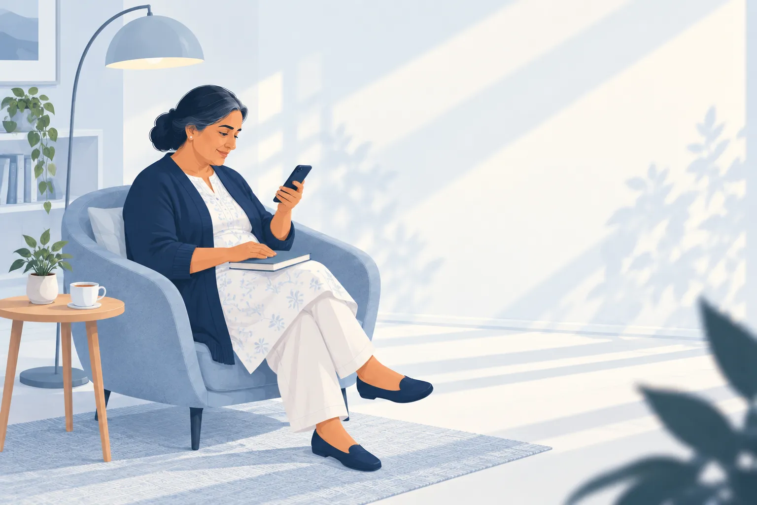 A woman settled in an armchair under a floor lamp reads a message on her phone with a small relieved smile, tea and a book beside her.